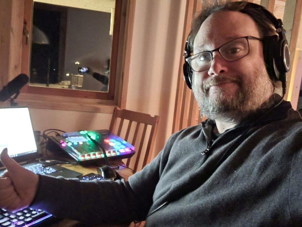 En bild på mig, Erik Zalitis, framför mikrofonen på familjens landställe i norra Sverige. Inspelning av ljud pågår.